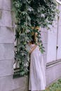 A Woman Leaning on Wall Under a Green Plant