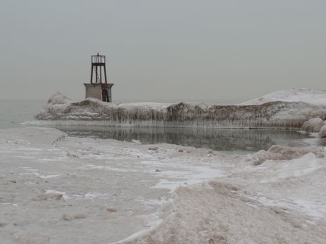 A serene frozen landscape showcasing an icy tower by the waterfront during winter.