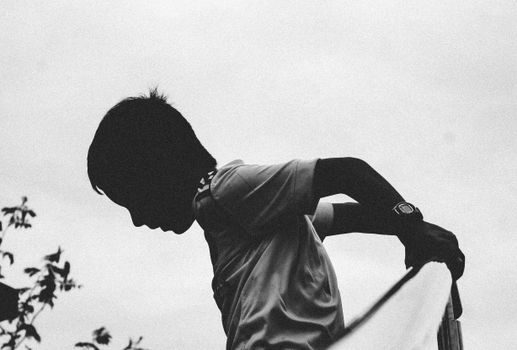A captivating silhouette of a child reaching out outdoors, captured in black and white.