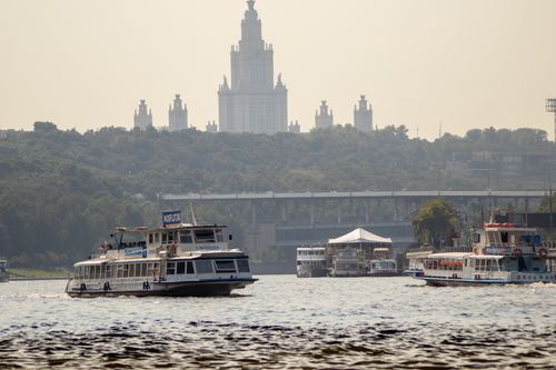 Free Boats navigate the river with Moscow State University in the distance, creating a serene scene. Stock Photo