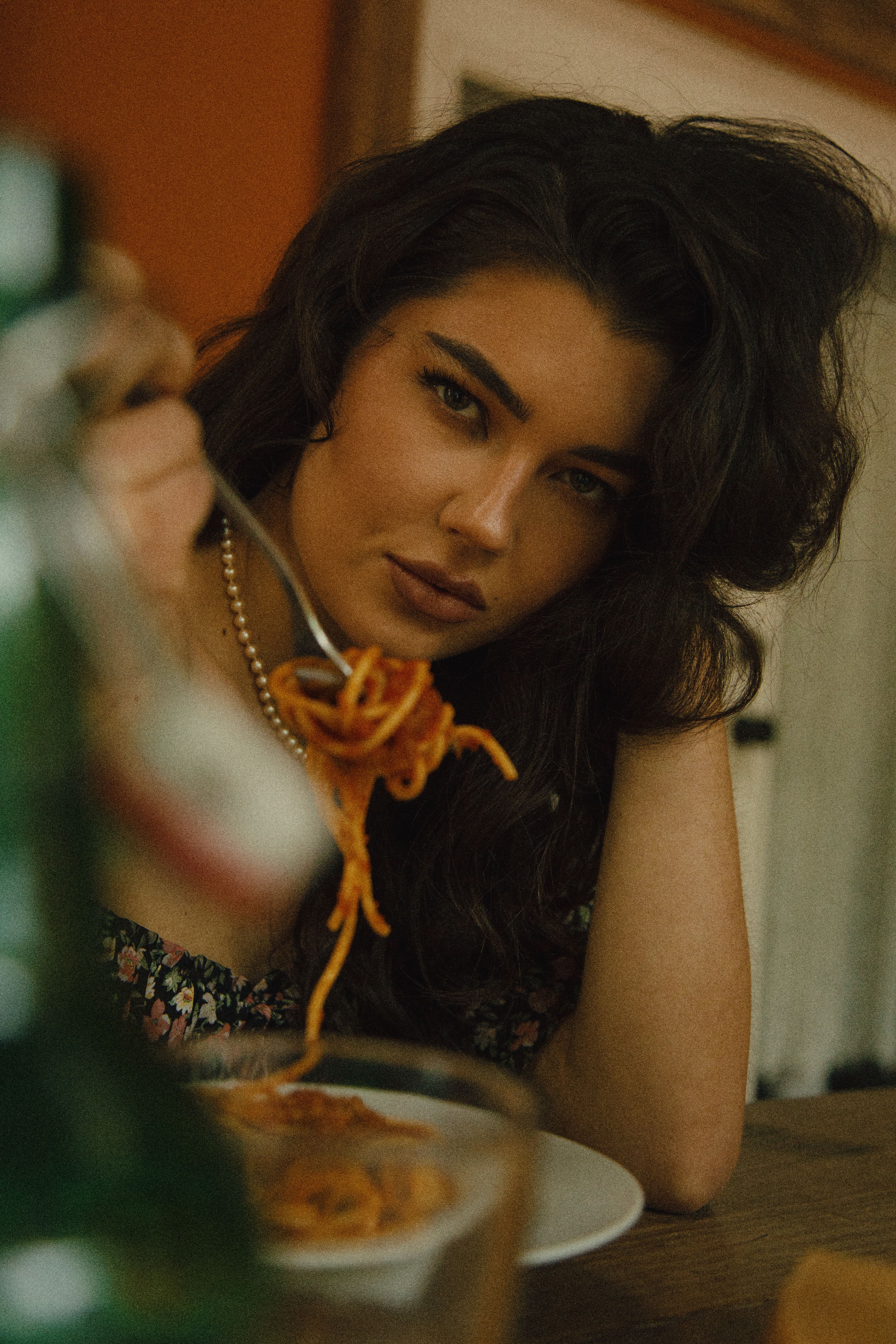 A woman savoring a plate of spaghetti in a warm, inviting atmosphere indoors.