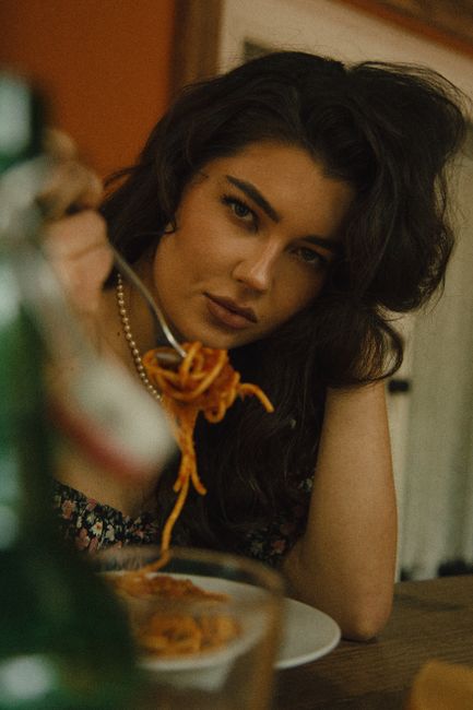 A woman savoring a plate of spaghetti in a warm, inviting atmosphere indoors.