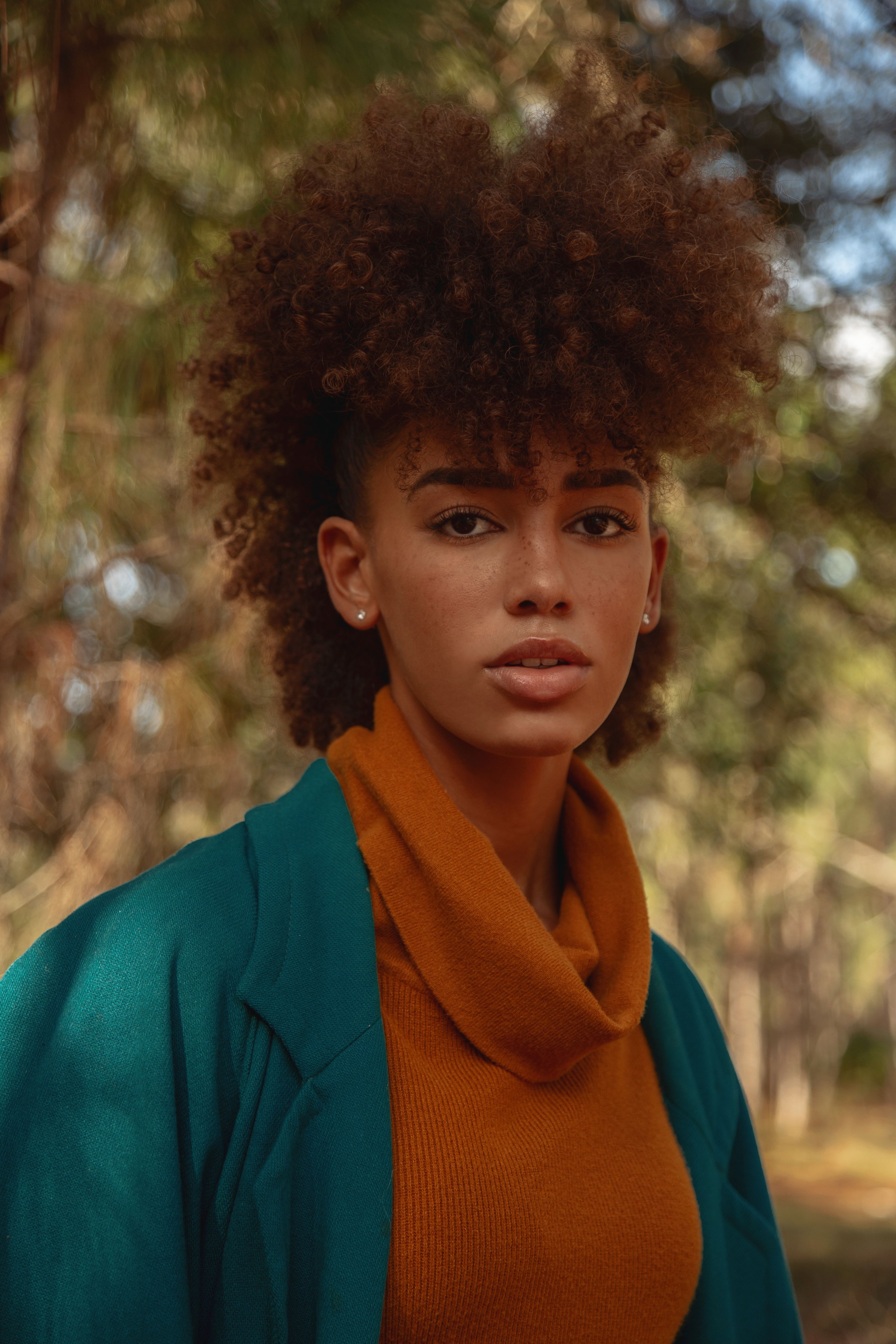 Portrait of a fashionable young woman with afro hair, posing outdoors in natural light