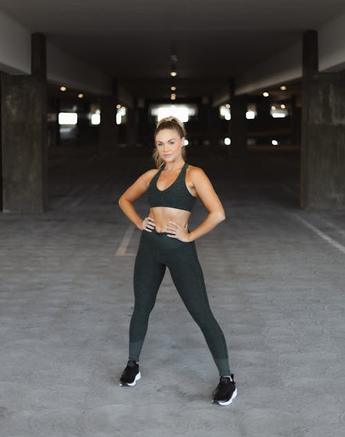 Woman in Black Tank Top and Black Pants Standing on Gray Concrete Floor