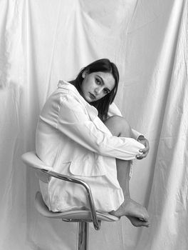Stunning monochrome portrait of a woman seated in a minimalist studio setting.