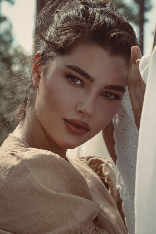 Free Close-up outdoor portrait of a young woman with striking features and brown hair, exuding elegance. Stock Photo