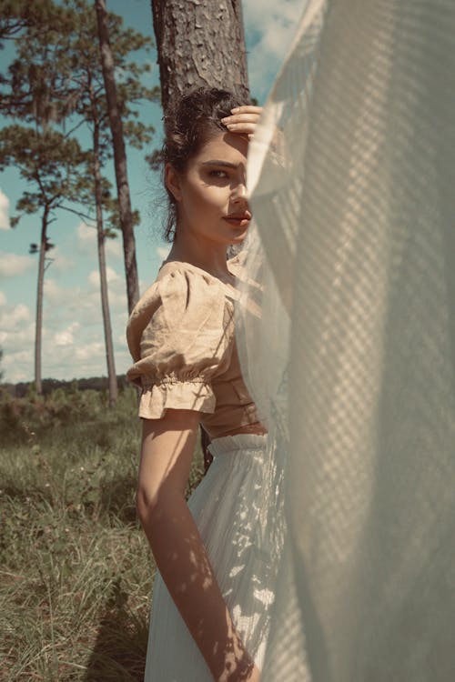 Woman in White Dress Standing on Green Grass Field