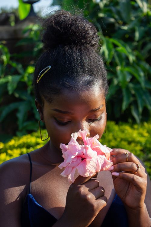 Free A serene portrait of a woman outdoors, enjoying the scent of a pink flower. Stock Photo