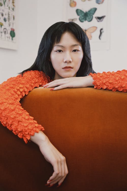 Woman in Red Long Sleeve Shirt Lying on Brown Couch