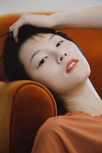 An elegant portrait of a woman in Asian fashion reclining in a relaxed pose indoors.