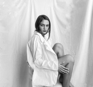 Woman in White Robe Standing Beside White Curtain