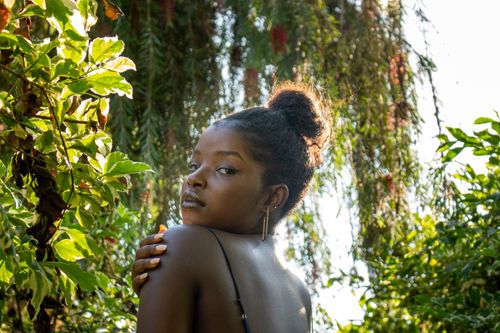 Free Portrait of a woman with a serene expression surrounded by lush greenery. Stock Photo