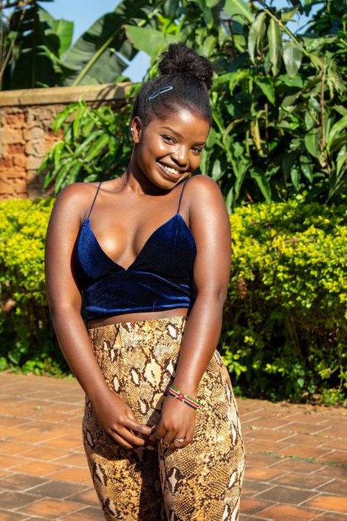 Free Fashionable young woman smiling outdoors in Seeta, Uganda amidst lush greenery. Stock Photo
