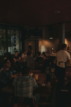 Group of adults enjoying a cozy evening in a dimly lit restaurant with a warm ambiance.