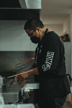 Chef preparing food in a modern kitchen, focused on culinary craft.