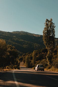 A scenic mountain road at sunrise, capturing a car journey through lush landscapes and inviting travel adventure.