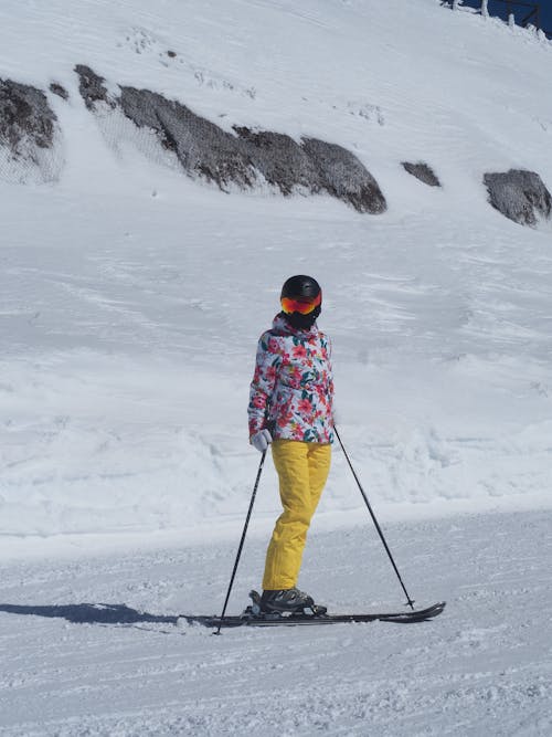 Person in Blue Jacket and Black Pants Riding Ski Blades on Snow Covered Ground