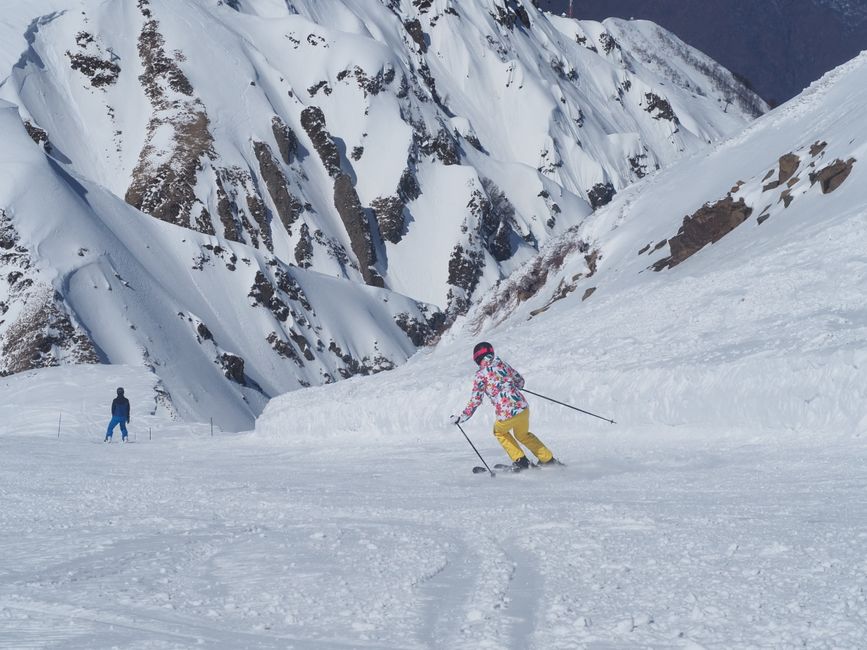 Skiers on the slopes of Gudauri Ski Resort in the snowy mountains of Georgia, with chairlifts visible.