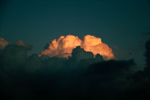Free A stunning view of dark, fluffy clouds with a warm glow from the sunset, creating a dramatic contrast. Stock Photo