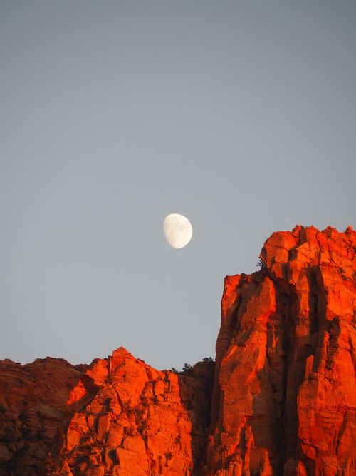 Free Scenic view of red rock cliffs at sunset with the moon in Utah. Stock Photo
