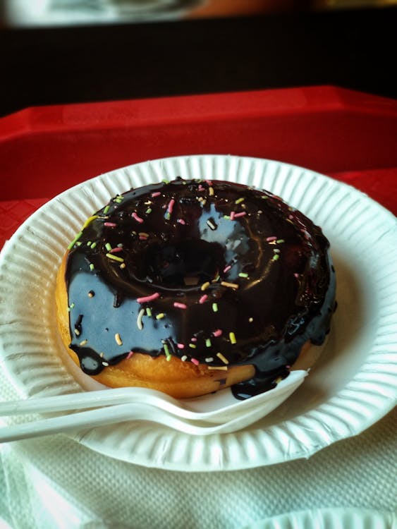 둥근 종이 접시와 플라스틱 숟가락과 포크 위에 초콜릿 도넛