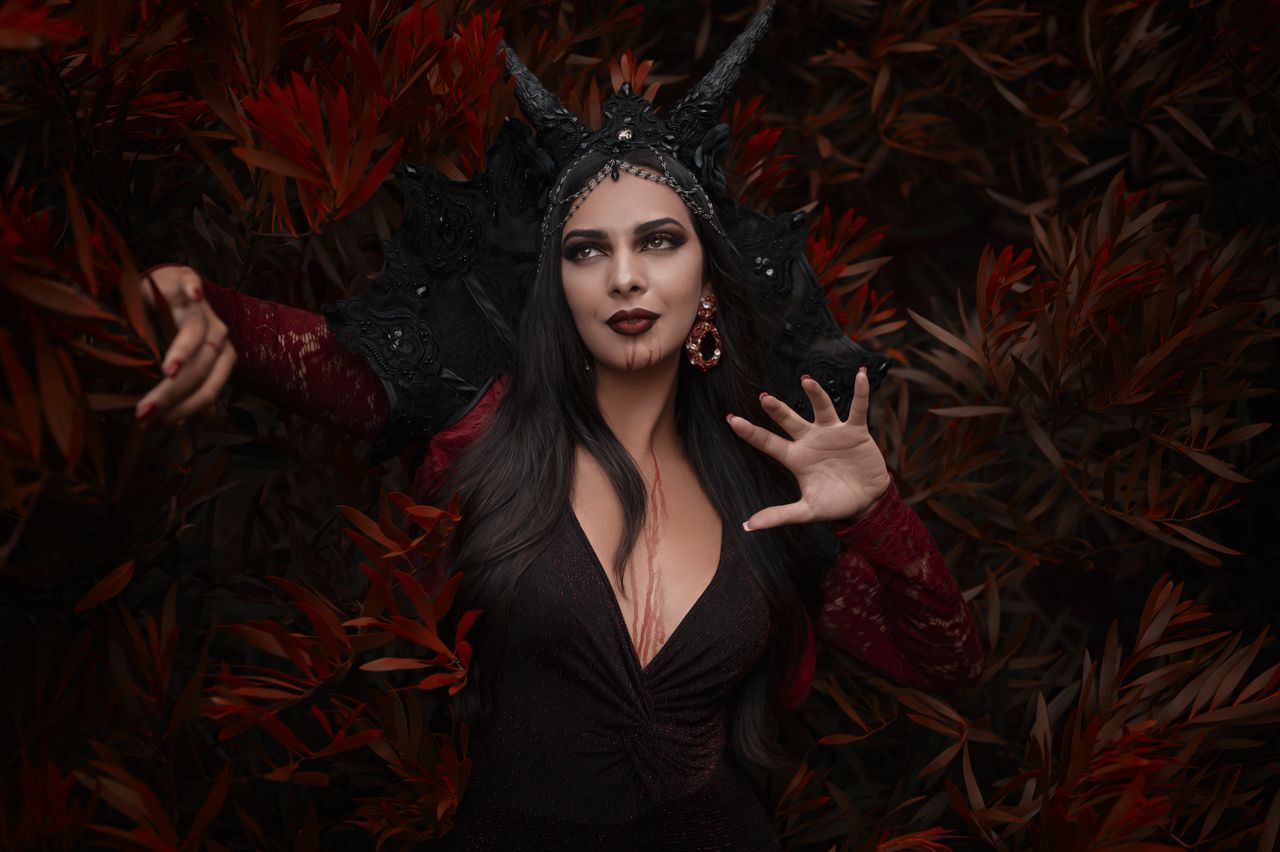 mysterious vampire woman posing in the forest with a dark costume