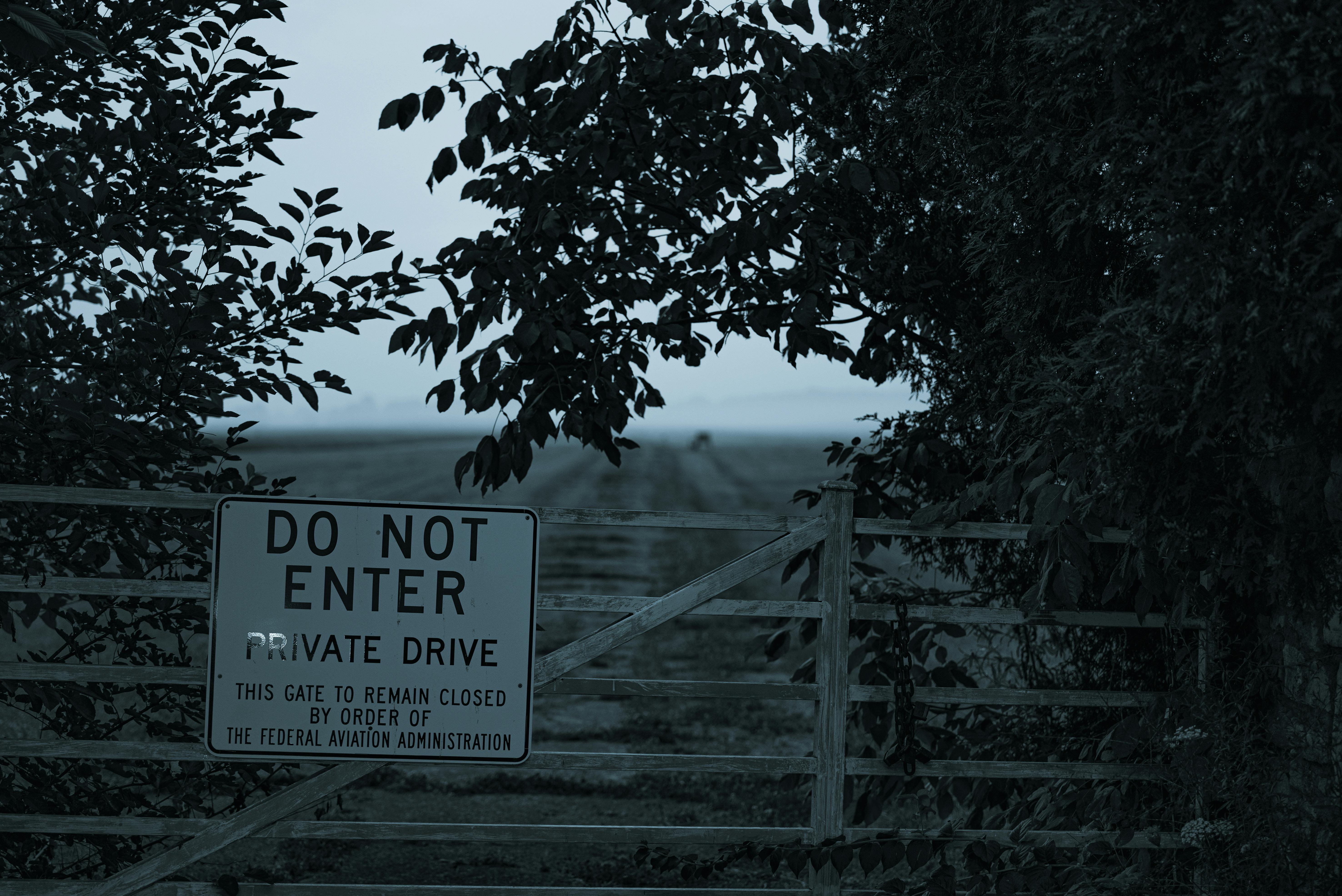 Grayscale Photo of Wooden Fence With Do Not Enter Signage