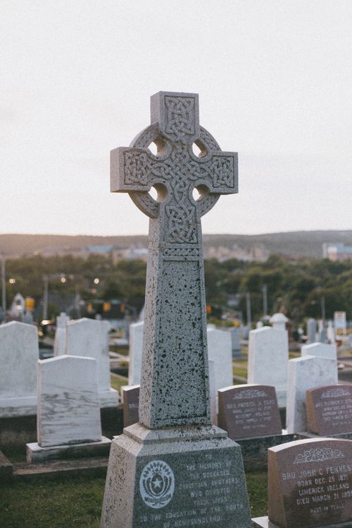 Free Celtic cross tombstone in a tranquil cemetery at dusk, symbolizing heritage and remembrance. Stock Photo
