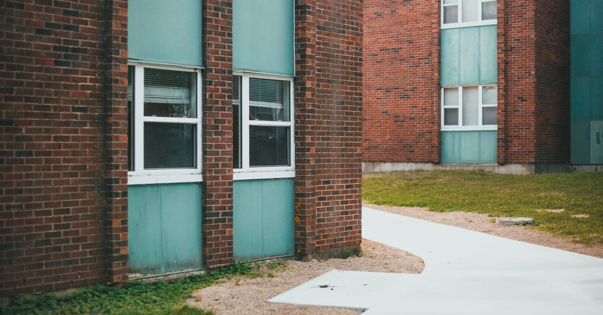 Contemporary building facade with brick and teal panels, showcasing urban architecture.