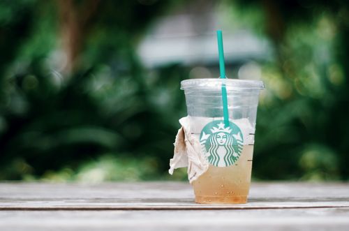 Free Close-up of an iced drink in a disposable Starbucks cup on a wooden table outdoors. Stock Photo