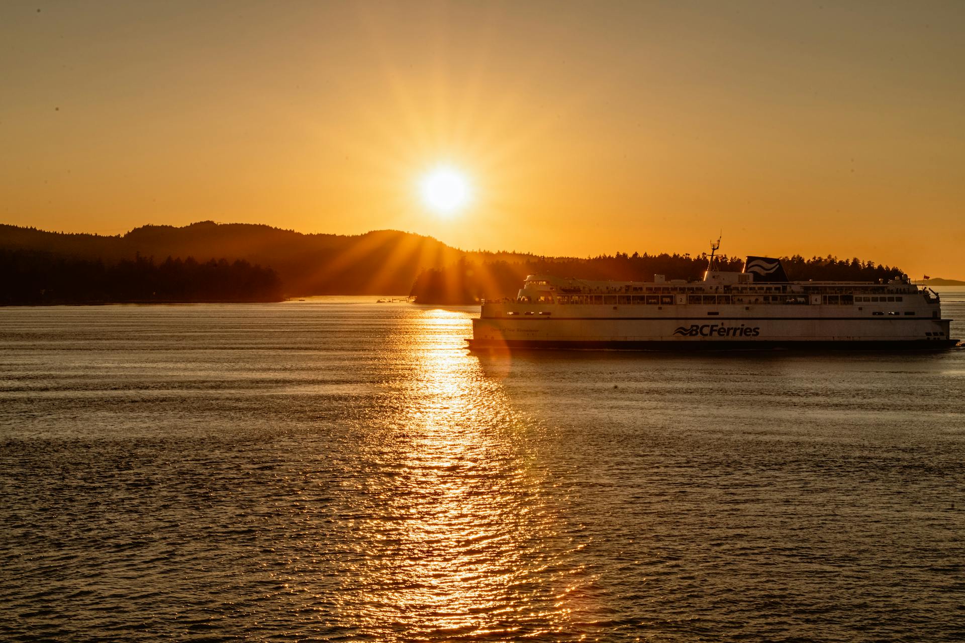 A BC Ferries ship sailing during a stunning golden sunset in BC, Canada.