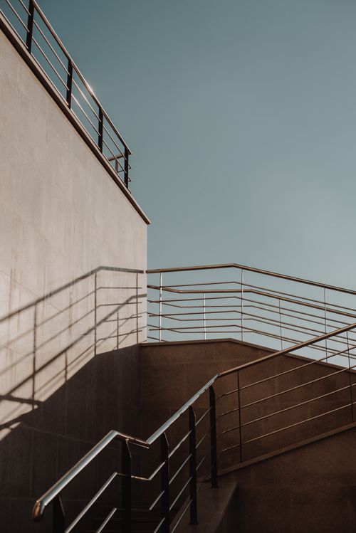 Free A minimalist outdoor staircase with steel railings casting shadows in daylight. Stock Photo