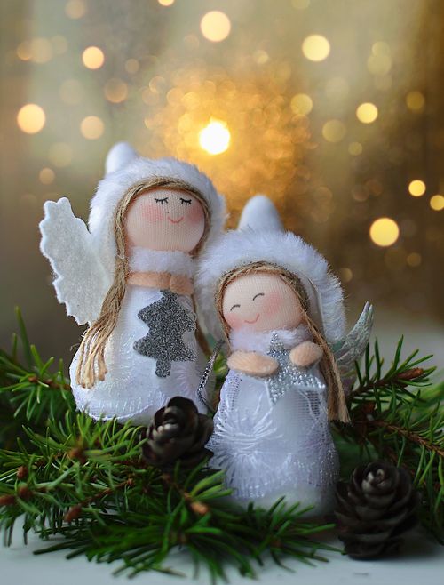 Free Adorable angel figurines surrounded by evergreen branches and pinecones, perfect for holiday decor. Stock Photo