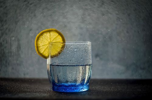 Free Close-up of a water glass with a lemon slice, showcasing vibrant splashes and texture. Stock Photo