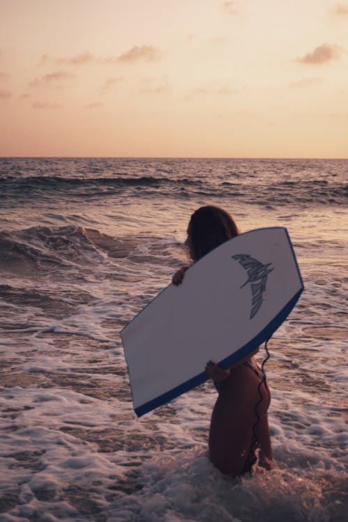 Woman in Brown Bikini Holding White Surfboard 