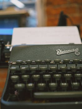 A close-up of a classic Rheinmetall typewriter with paper loaded, indoors.