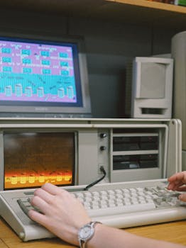 Close-up of hands interacting with a retro computer, showcasing vintage technology.