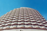 这是一张现代建筑的低角度照片，弧形阳台映衬着清澈的蓝天