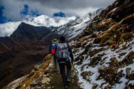 两名徒步旅行者在陡峭的山区沿着雪道行进，天空宜人