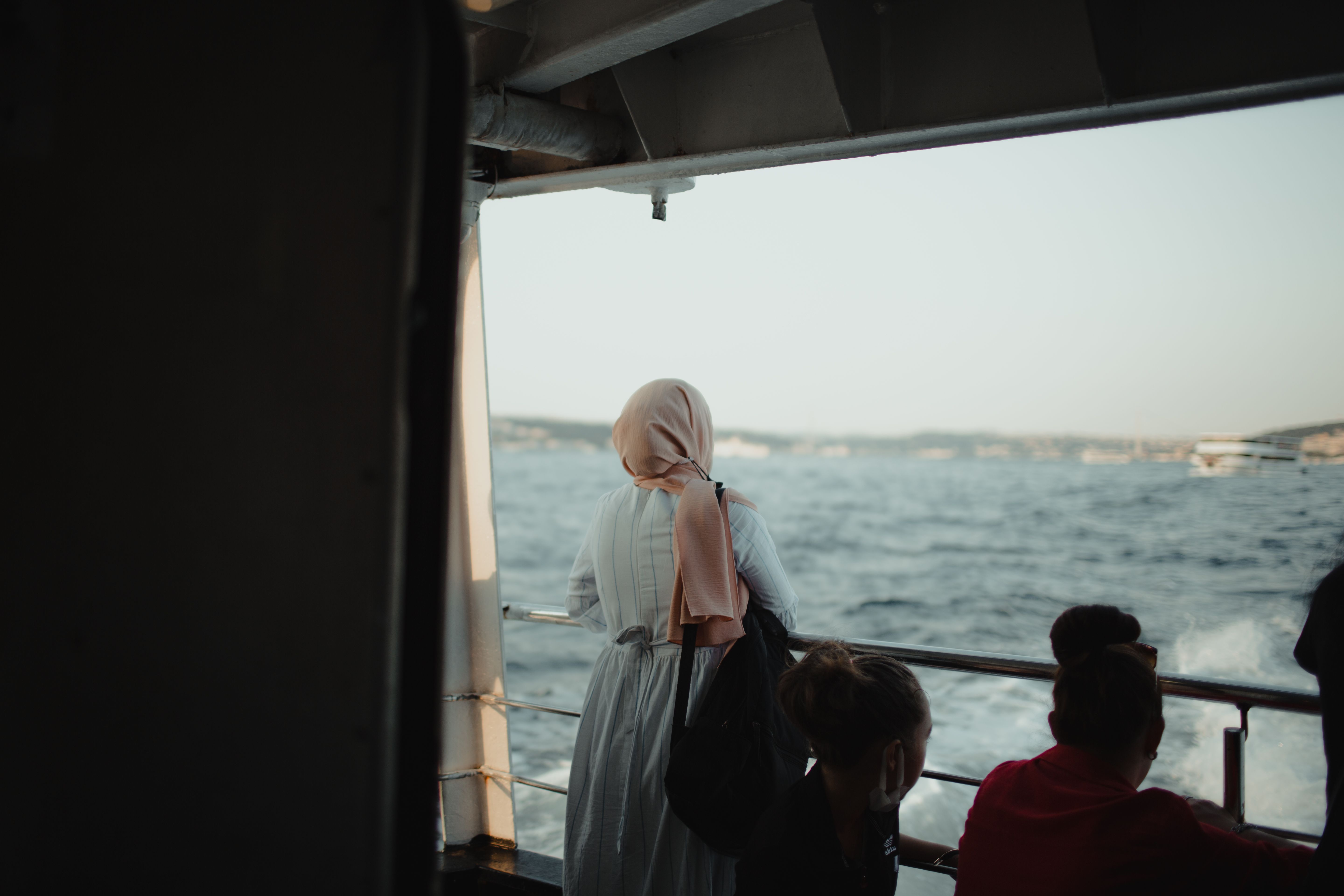 A woman in a hijab gazes at the Bosphorus from a ferry in Istanbul, Türkiye.