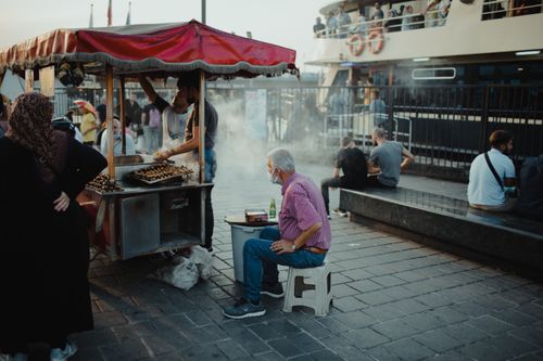 Free Street food vendor in Istanbul serving customers at the harbor with a bustling atmosphere. Stock Photo