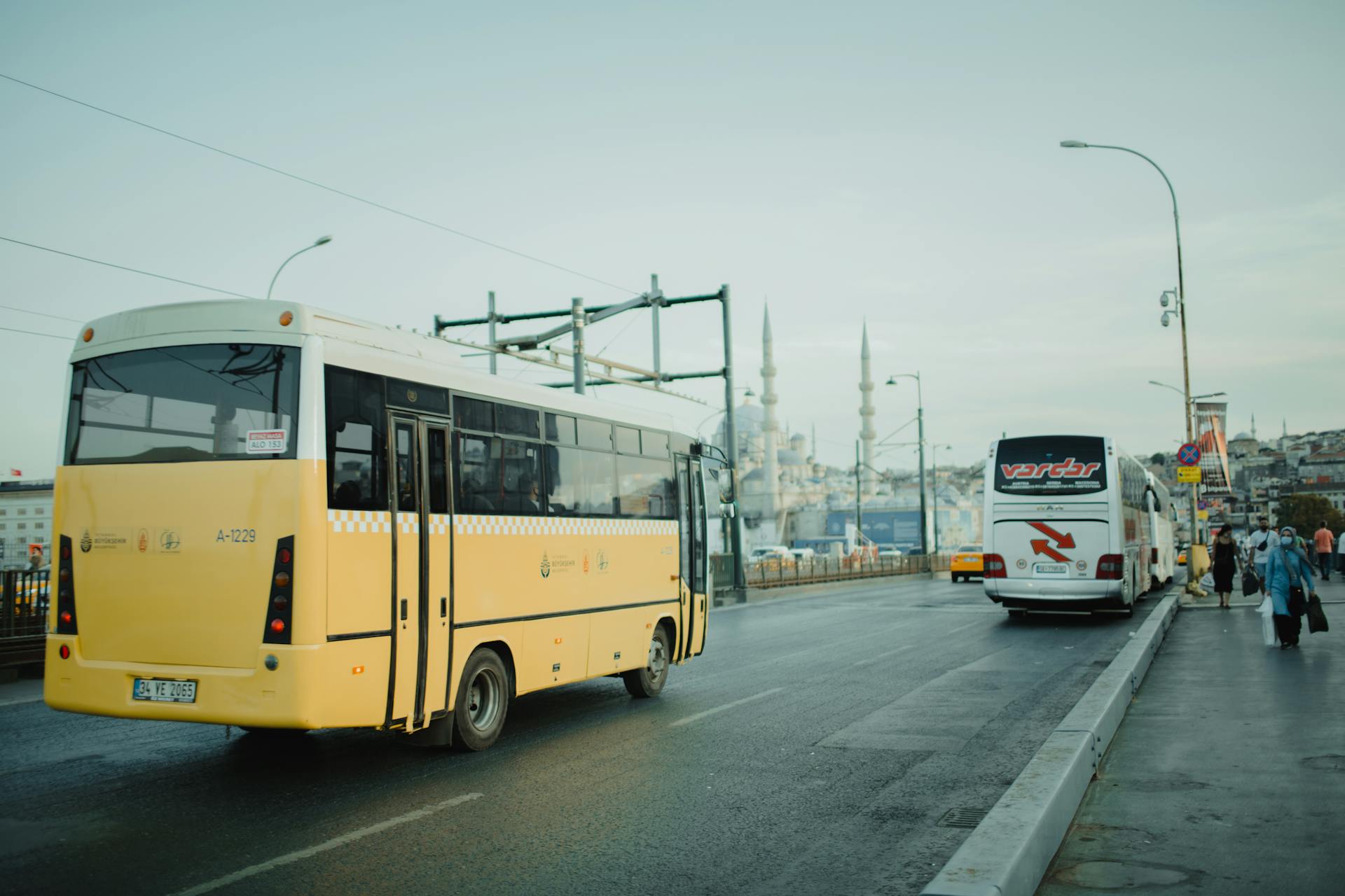 City scene in Istanbul featuring buses on a bridge with mosque in the background.