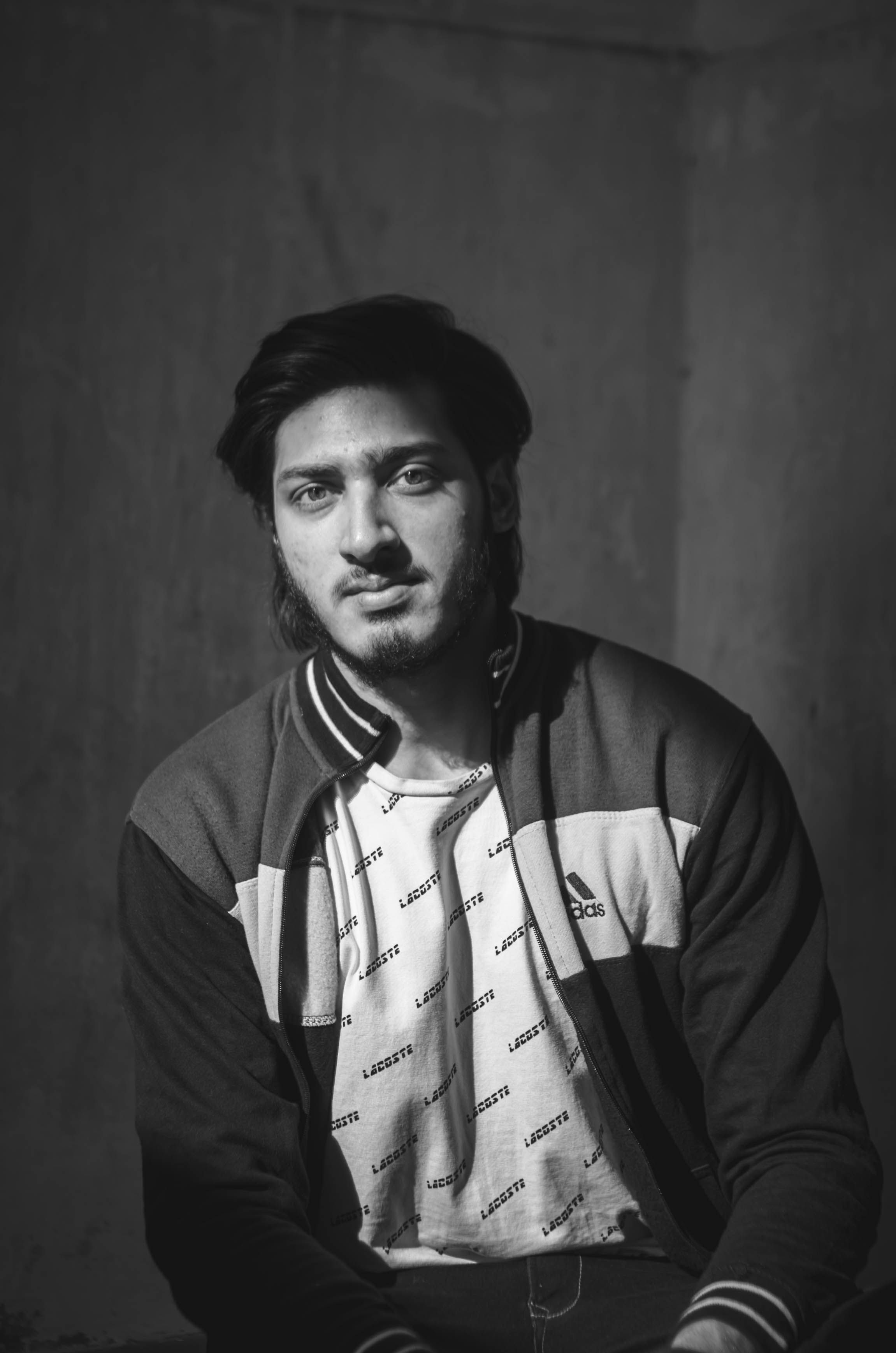 Black and white portrait of a man in a jacket sitting and looking serious indoors.