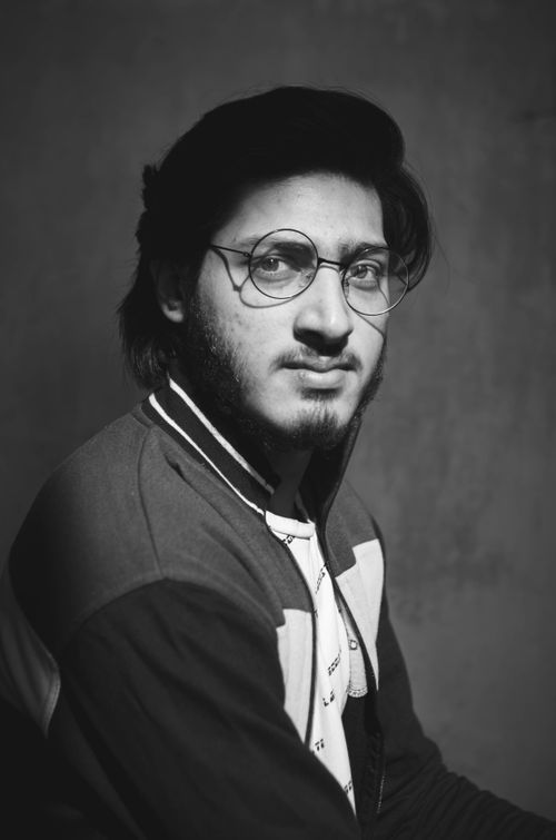 Free Black and white studio portrait of a young man wearing glasses, looking confidently into the camera. Stock Photo