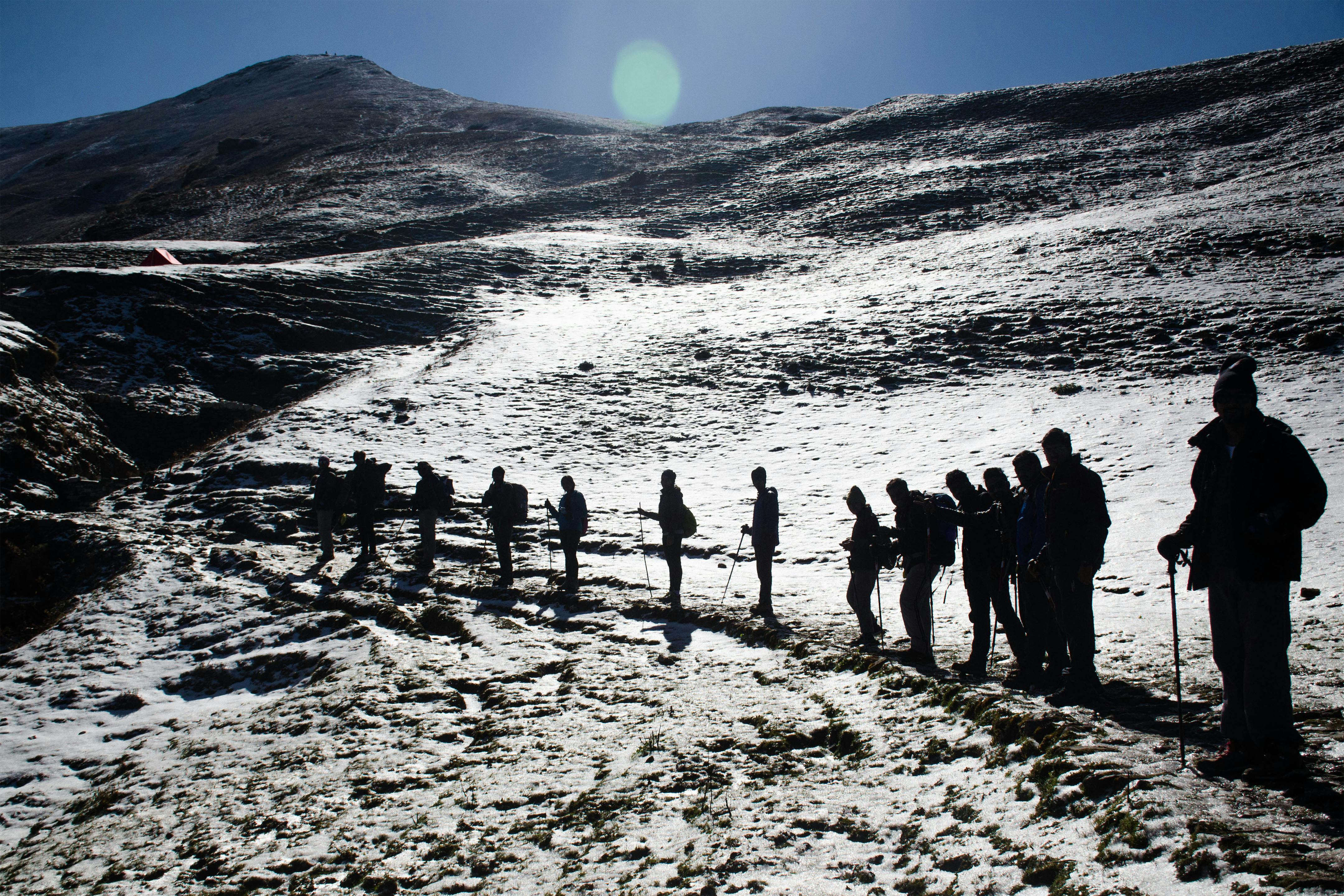 徒步旅行者的剪影在晴朗的天空下穿越雪山景观