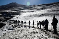在晴朗的天空下，徒步旅行者的剪影穿越雪山景观