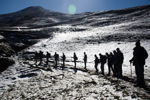 Free Silhouetted hikers traverse a snowy mountain landscape under clear skies. Stock Photo
