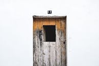 一扇质朴的木制门油漆剥落，白色墙上挂着数字“11”的标志