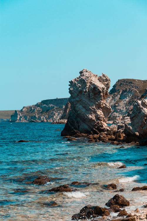 Brown Rock Formation on Blue Sea Under Blue Sky