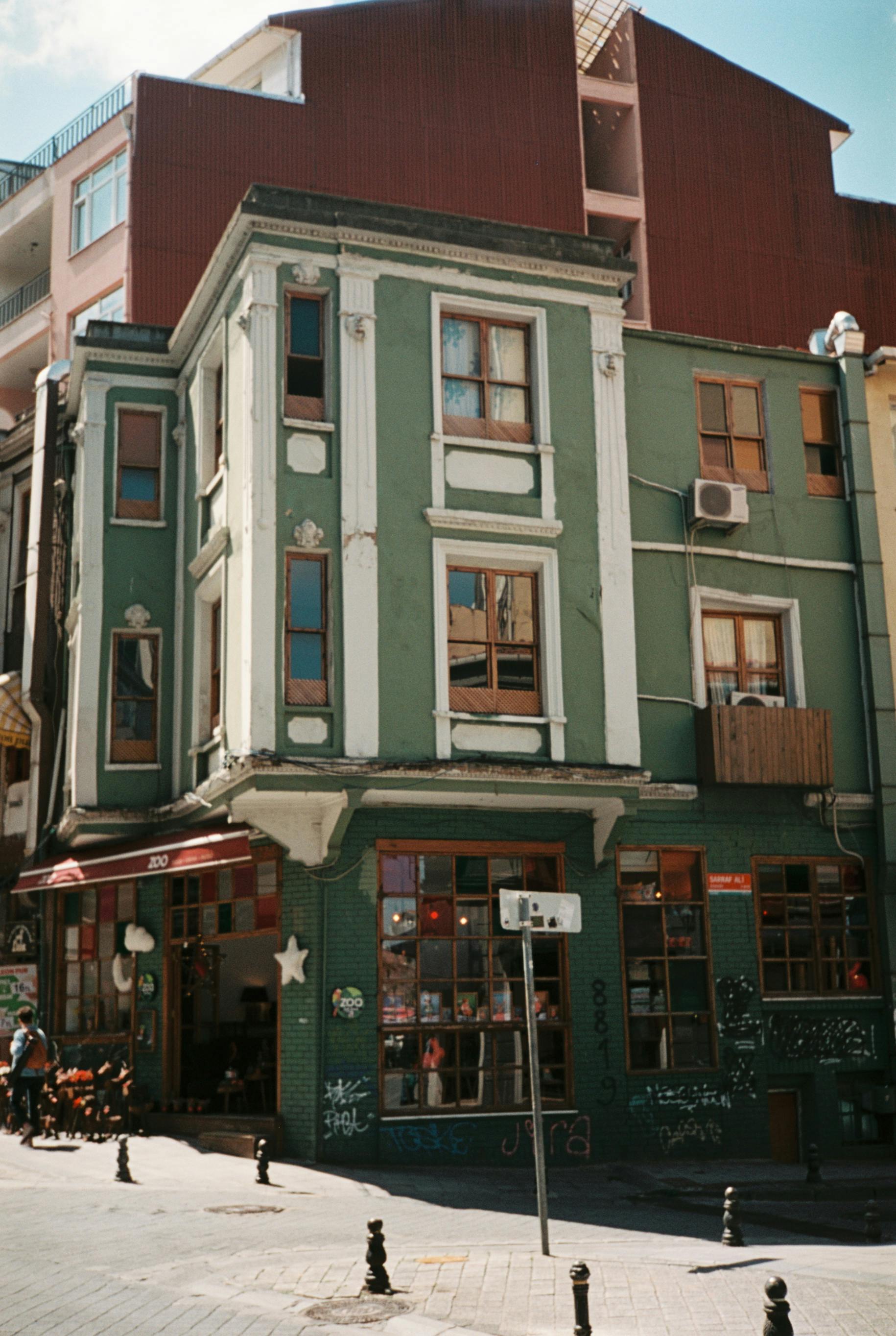 Free A vintage green townhouse with graffiti on a bustling city street corner. Stock Photo